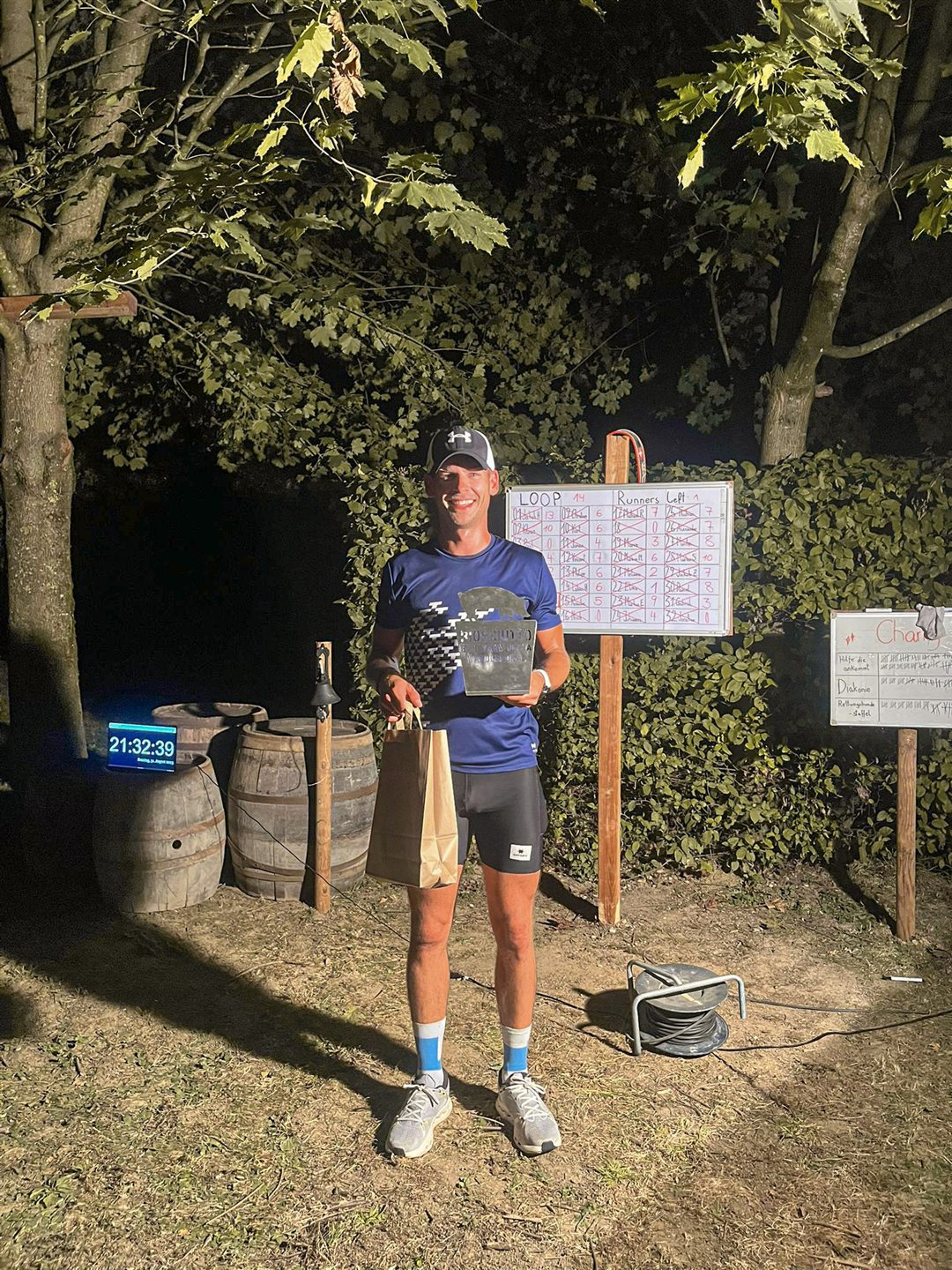 Michael Lehner, Sieger des Biosciutto Backyard 2025, mit Pokal vor der Rundentafel (Loop 14)