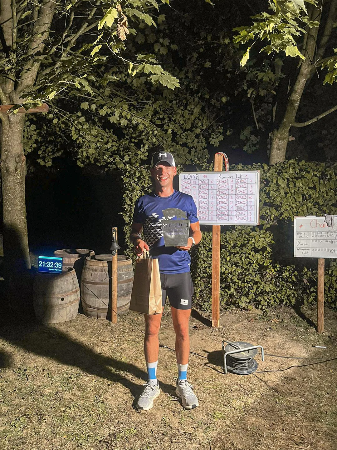 Michael Lehner, Sieger des Biosciutto Backyard 2025, mit Pokal vor der Rundentafel (Loop 14)