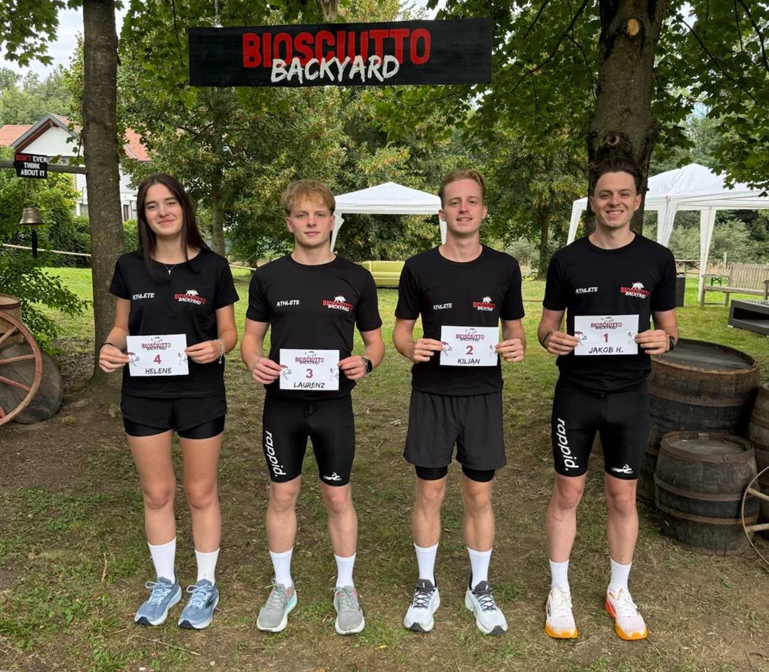 Jakob, Kilian, Laurenz und Helene mit Startnummern vor dem Biosciutto-Backyard-Torbogen